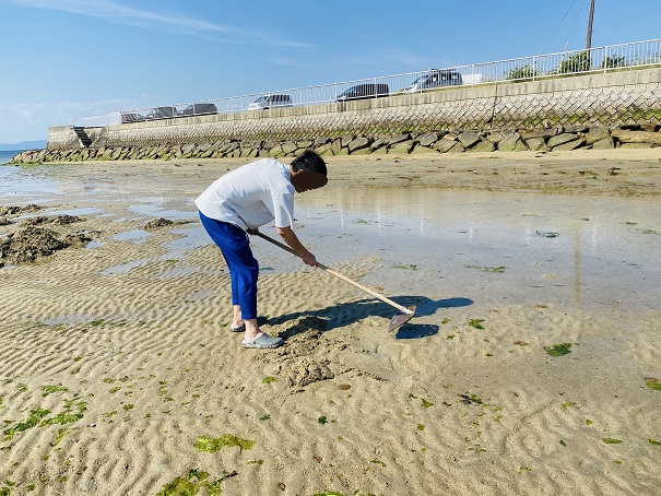 ジョレンで砂地の表面を削る綾川